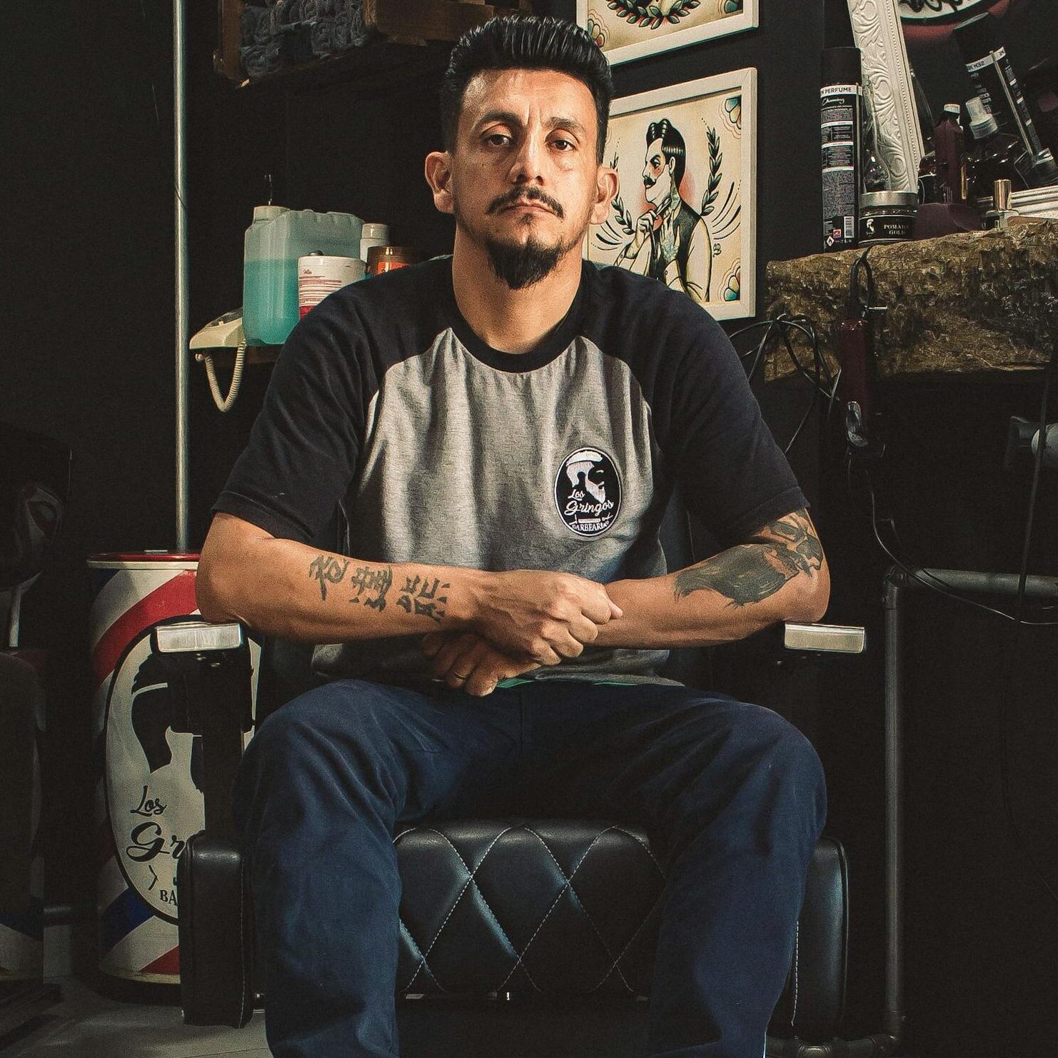 Man seated in a barber chair surrounded by retro decor inside a classic barbershop.